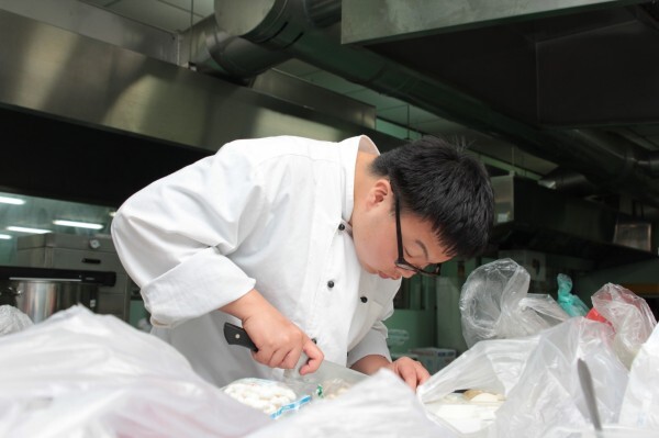 中台科技大學食品科技系學生胡凱寧先天弱視，必須彎腰才能看清食材。（呂哲維提供）