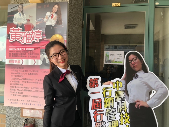 第一屆行銷達人-黃雅婷與牆面招牌及人型立牌合影