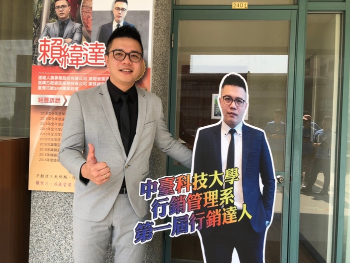 第一屆行銷達人-賴緯達與牆面招牌及人型立牌合影