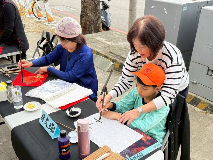 書藝精湛的書法老師與學童現場揮毫寫書法圖片