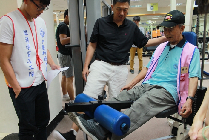 魏守群主任指導阿公使用腿屈伸訓練器，鍛練股四頭肌