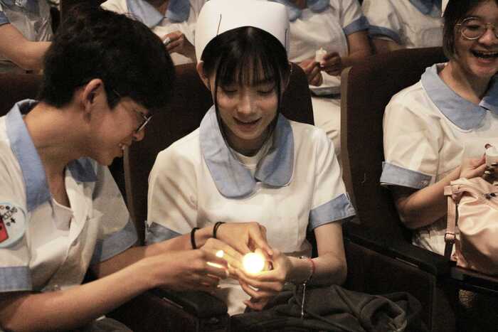 學生相互傳遞象徵生生不息的薪火蠟燭圖片