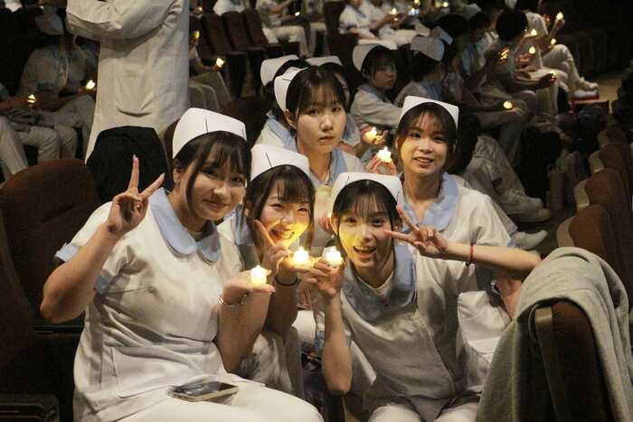 學生相互傳遞象徵生生不息的薪火蠟燭圖片